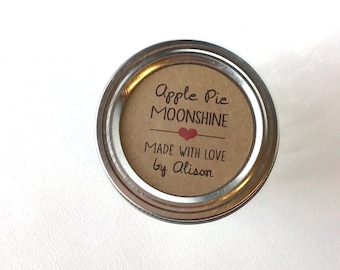 May include: A silver jar lid with a brown label that reads "Apple Pie Moonshine Made with Love by Alison". The label has a red heart.