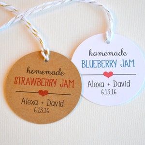Puede incluir: Dos etiquetas de regalo redondas con cuerda. Una etiqueta es marrón con el texto "homemade STRAWBERRY JAM Alexa + David 6.13.16". La otra etiqueta es blanca con el texto "homemade BLUEBERRY JAM Alexa + David 6.13.16".