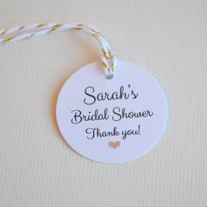 Könnte beinhalten: Runder weißer Dankesanhänger mit dem Text "Sarah's Bridal Shower Thank you!" und einem kleinen rosa Herz.