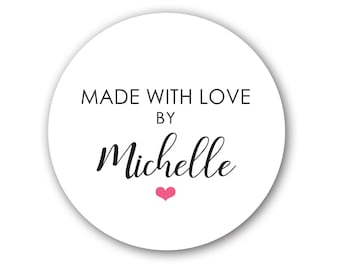 Puede incluir: Una pegatina blanca y circular con el texto "MADE WITH LOVE BY Michelle" en negro. Un pequeño corazón rosa está debajo del nombre. La pegatina tiene una ligera sombra, creando un efecto 3D.
