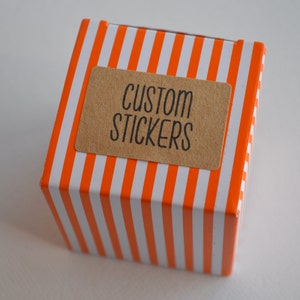 May include: A small orange and white striped box with a brown label that says "CUSTOM STICKERS".