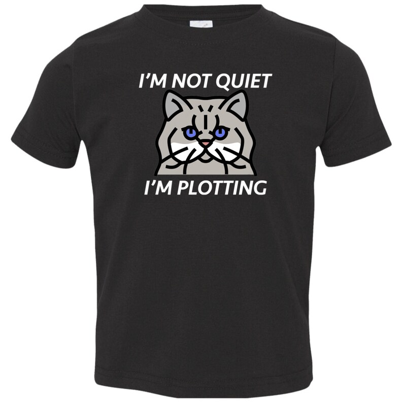 Pode incluir: Camiseta preta para crian&ccedil;a pequena com uma ilustra&ccedil;&atilde;o de um gato branco e o texto "N&atilde;o estou quieto, estou a planear".
