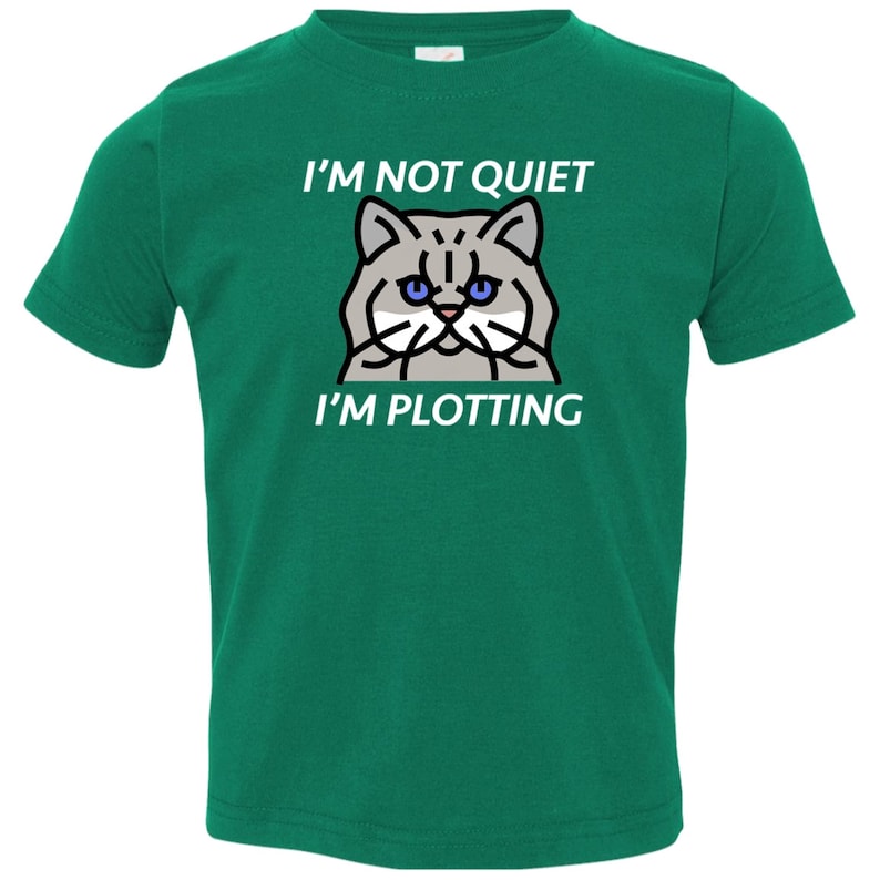 Pode incluir: Uma camiseta verde para crian&ccedil;as pequenas com uma ilustra&ccedil;&atilde;o de um gato branco e o texto "N&atilde;o estou quieto, estou tramando".