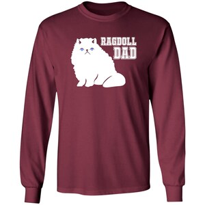 May include: A maroon long-sleeved t-shirt with a white silhouette of a Ragdoll cat and the text "Ragdoll Dad" in white.