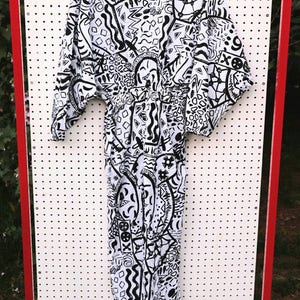 May include: A white jumpsuit with a black and white abstract pattern. The pattern includes geometric shapes, lines, and swirls.