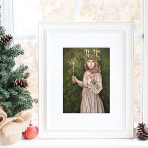 May include: A framed illustration of a woman wearing a wreath of greenery and candles on her head. She is holding a lit candle in her right hand and is standing in a forest setting. The illustration is painted in a realistic style with soft colors.