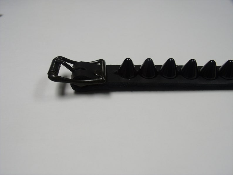 May include: Black leather bracelet with a silver buckle and black pyramid-shaped studs.