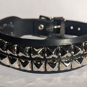 May include: A black leather choker with two rows of silver pyramid-shaped studs.