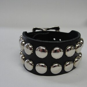 May include: Black leather bracelet with a silver buckle and rows of silver studs.