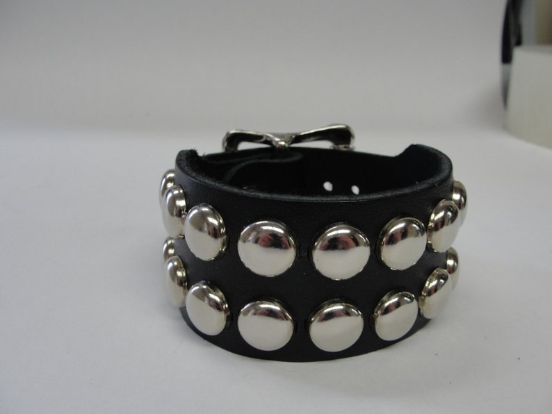 May include: Black leather bracelet with a silver buckle and rows of silver studs.