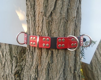 Puede incluir: Un collar de perro de cuero rojo y negro con detalles de metal plateado y dos grandes anillos en D plateados.