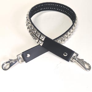May include: Black leather bag strap with silver pyramid studs. The strap has silver metal clasps on each end for easy attachment. The strap is designed to be used with a purse or handbag.