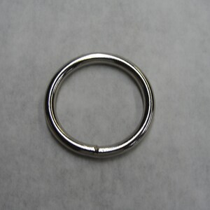 May include: A silver metal ring, also known as a key ring or split ring, is a simple, circular shape with a gap in the metal. It is commonly used for attaching keys, charms, or other small items.