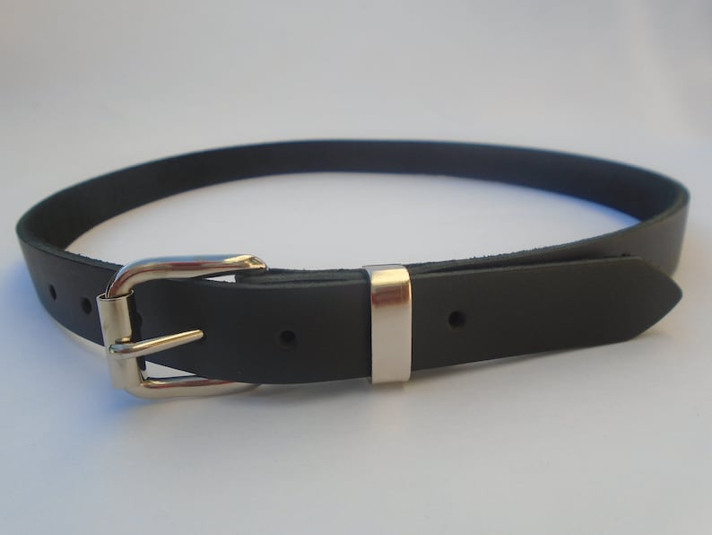 May include: A black leather belt with a silver buckle. The belt is approximately 2.5 cm wide and has a pointed end.