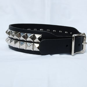 May include: A black leather belt with two rows of silver pyramid studs and a silver buckle.