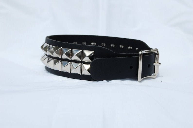 May include: A black leather belt with two rows of silver pyramid studs and a silver buckle.