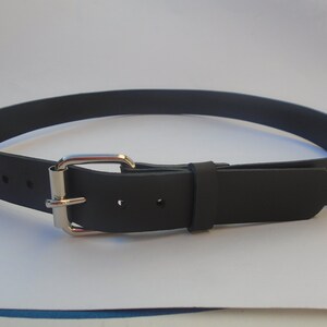 May include: A black leather belt with a silver buckle. The belt is approximately 2.5 cm wide.