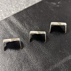 May include: Three silver metal buckle closures for leather goods, such as belts or straps.