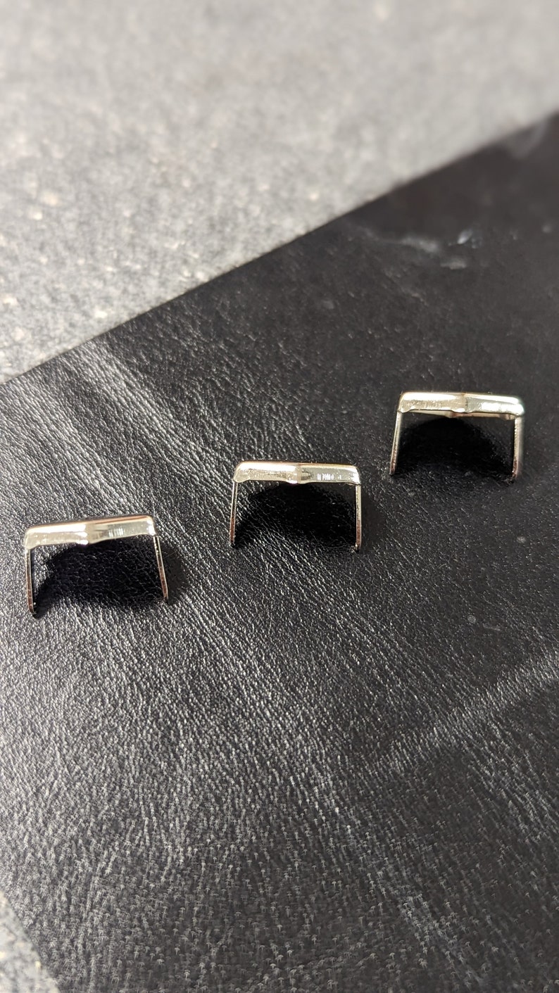 May include: Three silver metal buckle closures for leather goods, such as belts or straps.