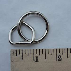 May include: A silver metal ring with a smaller, D-shaped ring attached to it. The rings are about 1 inch in diameter.