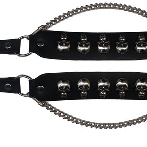 May include: Two black leather bracelets with silver skull accents and a silver chain. Each bracelet has six skull studs and a buckle closure.