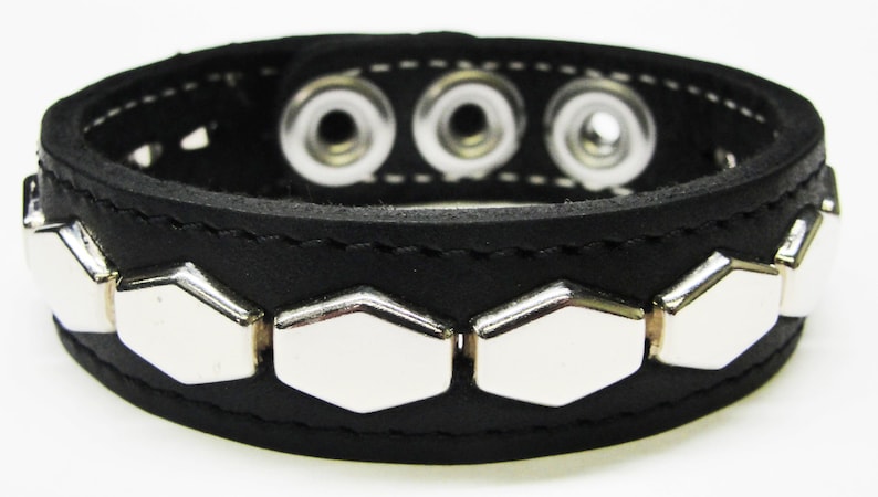 May include: Black leather bracelet with silver hexagonal studs and three snap closures.