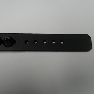 May include: Black leather bracelet with black studs and multiple holes for adjusting the size.