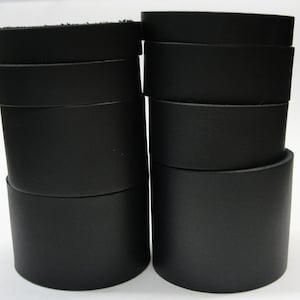 May include: Two stacks of black leather strips, each stack is about 10 strips high.