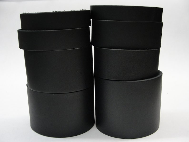 May include: Two stacks of black leather strips, each stack is about 10 strips high.