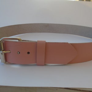 Pode incluir: Um cinto de couro rosa claro com uma fivela prateada.