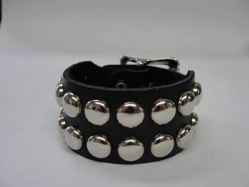 May include: A black leather bracelet with silver studs. The bracelet has a buckle closure.