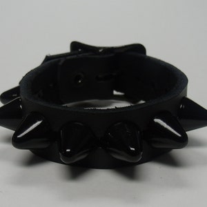 May include: Black leather bracelet with a buckle closure and black spikes.