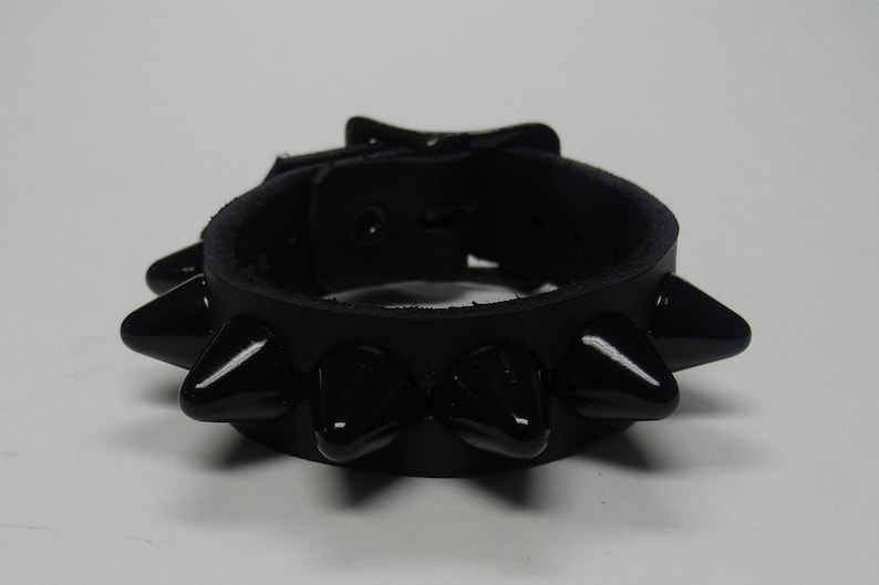 May include: Black leather bracelet with a buckle closure and black spikes.