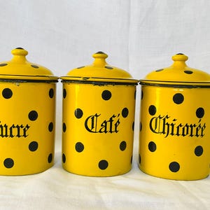 Puede incluir: Tres botes amarillos de esmalte con lunares negros y tapas. Los botes están etiquetados con "Sucre", "Café" y "Chicorée" en escritura negra. Un juego de almacenamiento de cocina vintage.