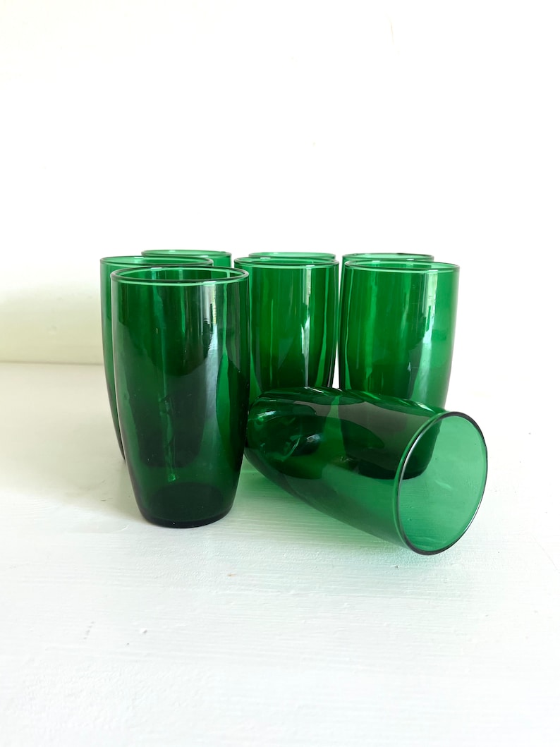 May include: Set of ten green glass tumblers. The glasses are tall and slender with a rounded bottom.