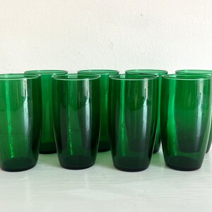 May include: Set of ten green glass tumblers. The glasses are clear and have a slightly rounded shape.