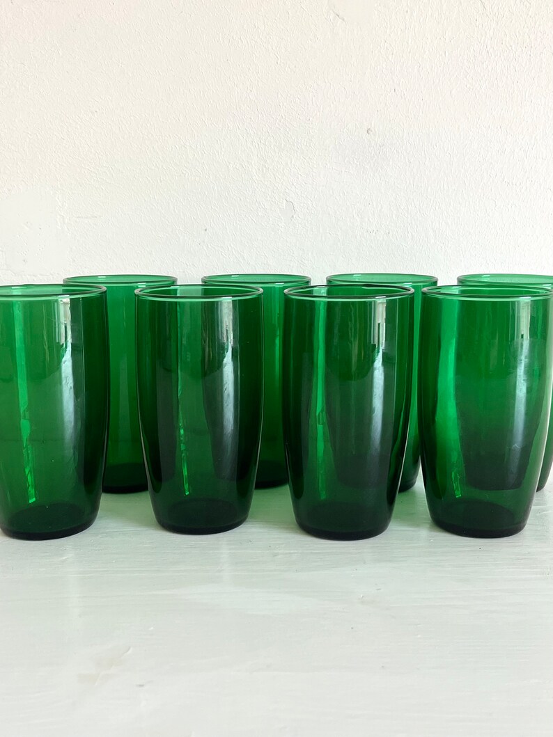 May include: Set of ten green glass tumblers. The glasses are clear and have a slightly rounded shape.