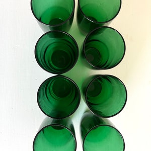 May include: Eight green glass tumblers, arranged in two rows of four, on a white surface.