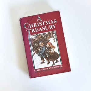 May include: A Christmas Treasury book with a burgundy cover. The cover features the title in white and green, and an illustration of two children carrying a Christmas tree in a snowy forest. Edited by Jack Newcombe.