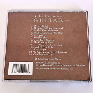 K&ouml;nnte beinhalten: Ein braunes CD-Geh&auml;use mit einem wei&szlig;en Etikett, auf dem "Christmas Guitar" steht und 13 Weihnachtslieder aufgelistet sind. Das Etikett enth&auml;lt auch einen Barcode und den Text "50-Plus Minutes of Music".