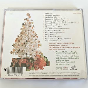K&ouml;nnte beinhalten: Ein CD-Geh&auml;use mit einem wei&szlig;en Weihnachtsbaum auf der Vorderseite und einer Liste von Weihnachtsliedern auf der R&uuml;ckseite. Die R&uuml;ckseite enth&auml;lt auch Informationen &uuml;ber die K&uuml;nstler, das Boston Pops Orchestra und den Tanglewood Festival Chorus, sowie die Aufnahmedetails.