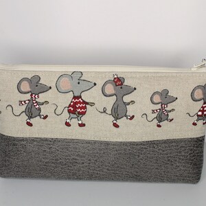 Könnte beinhalten: Eine graue Reißverschlusstasche mit einem oberen Teil aus beigefarbenem Leinenstoff, der ein sich wiederholendes Muster aus grauen Mäusen zeigt, die rote und weiße Schals und Pullover tragen. Der untere Teil der Tasche ist aus grauem, strukturiertem Stoff.
