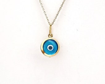 May include: A gold chain necklace with a blue evil eye pendant. The pendant is round and has a white center.