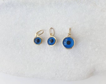 May include: Three gold evil eye pendants of different sizes. The pendants are blue with a white pupil and are set in a gold frame.