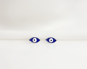 May include: A pair of silver earrings with blue evil eye charms. The earrings are small and delicate.
