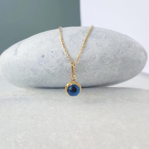 Pu&ograve; includere: Una collana con catena d'oro con un ciondolo blu a forma di occhio turco. Il ciondolo &egrave; circondato da una cornice dorata.