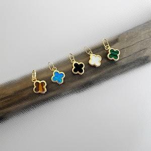 May include: Six gold clover charms with different coloured stones. The stones are green, white, black, blue, brown, and a light green.