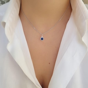 Pu&ograve; includere: Una collana a catena d'argento con un piccolo ciondolo blu a forma di occhio turco. La collana &egrave; indossata da una persona con una camicia bianca.