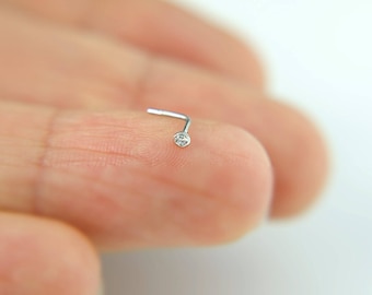May include: A silver nose ring with a small clear gemstone.