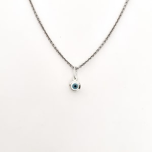 Può includere: Una collana con catena d'argento con un piccolo ciondolo a forma di occhio turco blu.